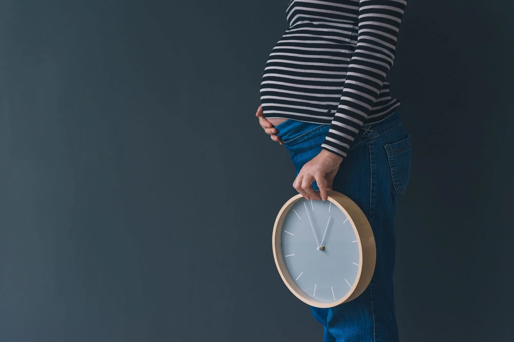 Pregnant female with vintage alarm clock