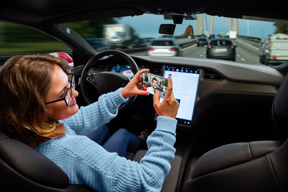 Woman communicates by video call while her car is driven by an autopilot. Self driving and autonomous vehicle concept